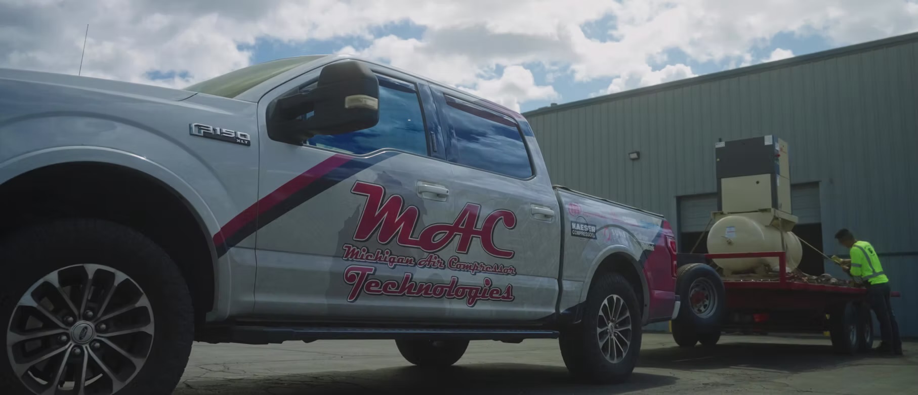 A MAC Technologies service truck and a technician moving an air compressor at a customer site
